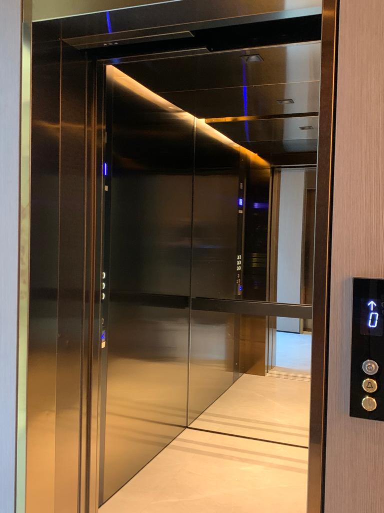 Bespoke DDA access step lift providing wheelchair access between levels in a public building. The step lift has steel painted framework with glass side panels and gate