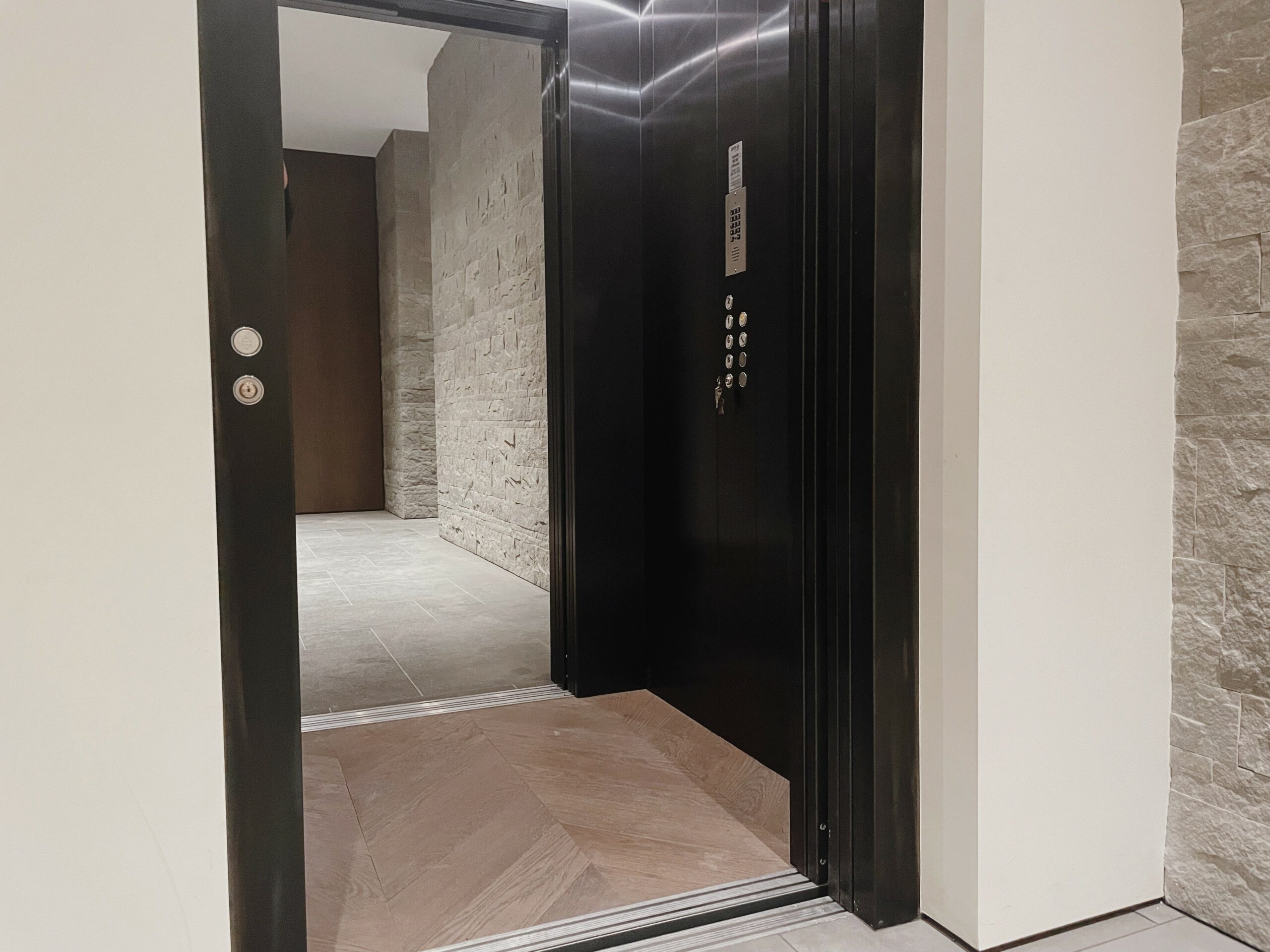 Pit less Step lift raised to the upper landing level of a commercial building entrance lobby, the lift is finished in Painted steel with glass side panels