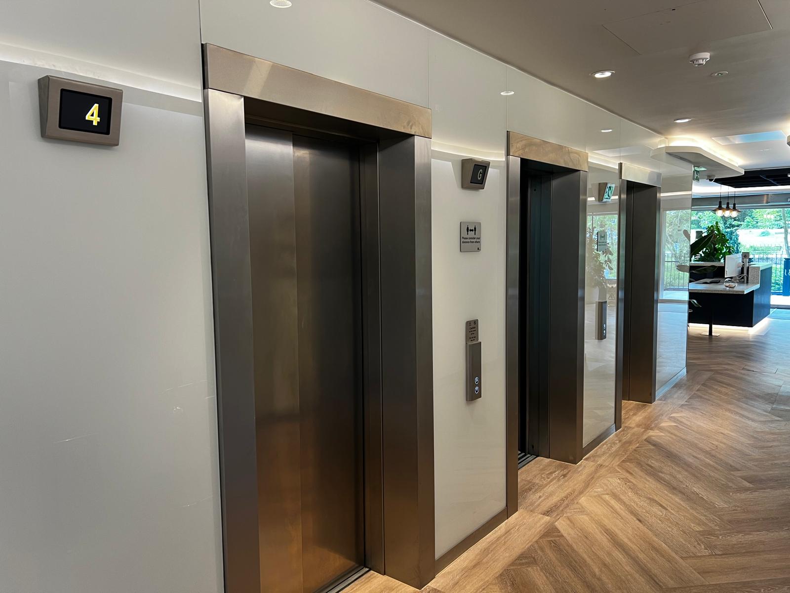Step lift sited in a rustic brick lift shaft. The wheelchair access lift is finished with fully glazed side panels and black painted steel
