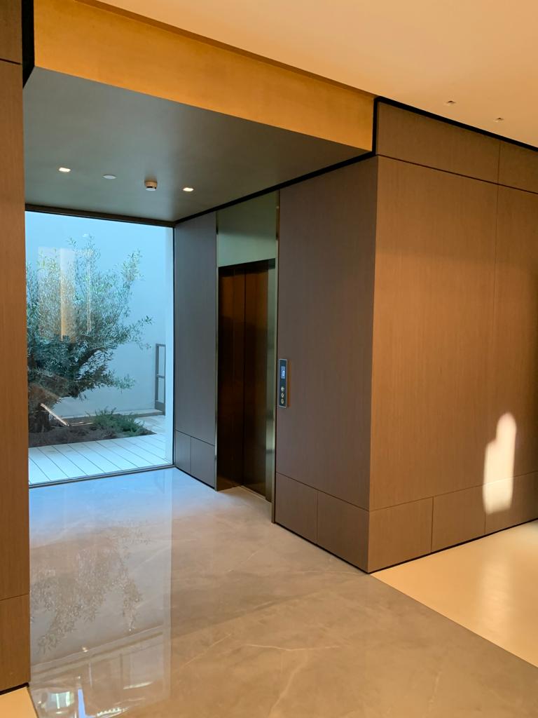 Bespoke DDA access step lift providing wheelchair access between levels in a public building. The step lift has steel painted framework with glass side panels and gate