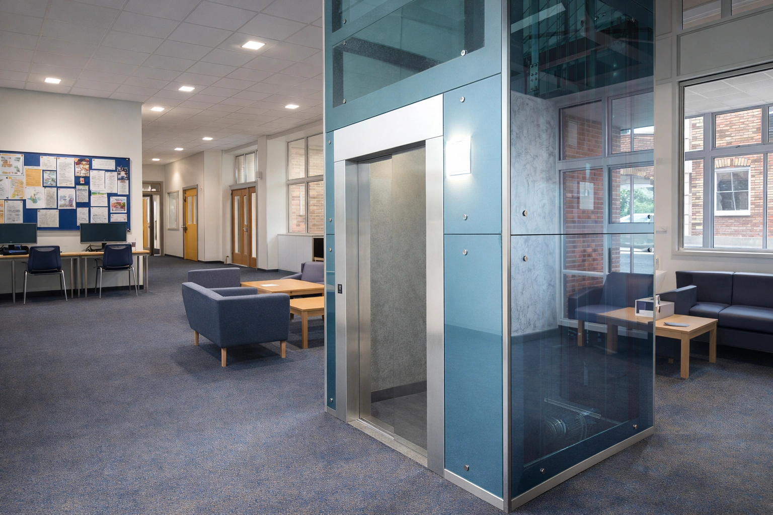 Step lift sited in a rustic brick lift shaft. The wheelchair access lift is finished with fully glazed side panels and black painted steel
