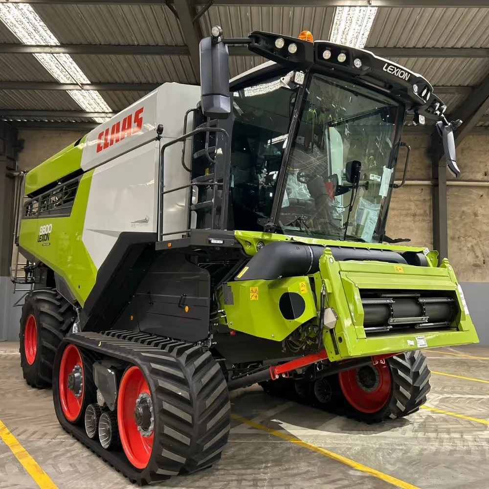 A large green and white combine harvester is parked inside an industrial building.