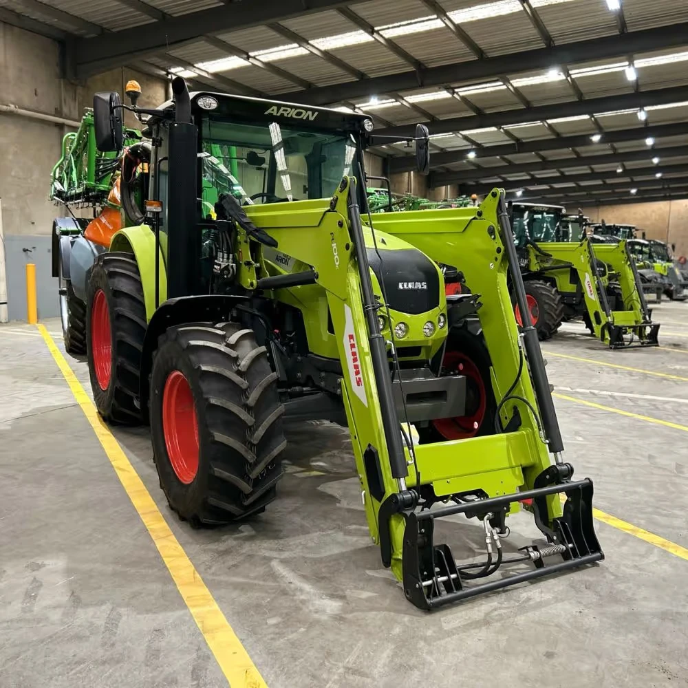 A green and black tractor with large red wheels is parked inside a warehouse.