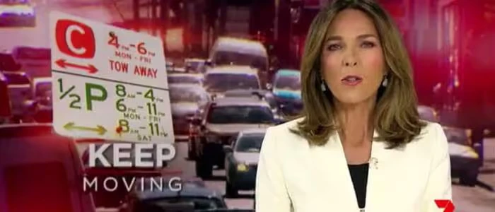 News anchor reporting on heavy traffic with a parking sign displayed.