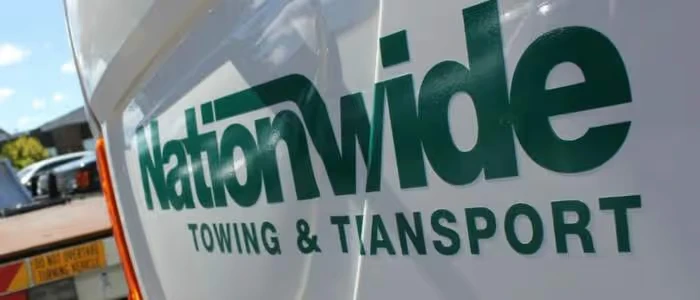 A tow truck with "Nationwide Towing & Transport" logo is parked outside.