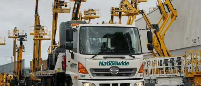 A large truck with "Nationwide" logo surrounded by numerous yellow construction lifts.