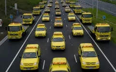 A fleet of yellow service vehicles drives down a multi-lane highway.