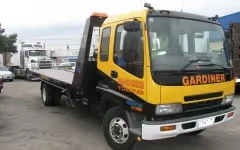 Tow truck parked in a lot with other vehicles in the background.