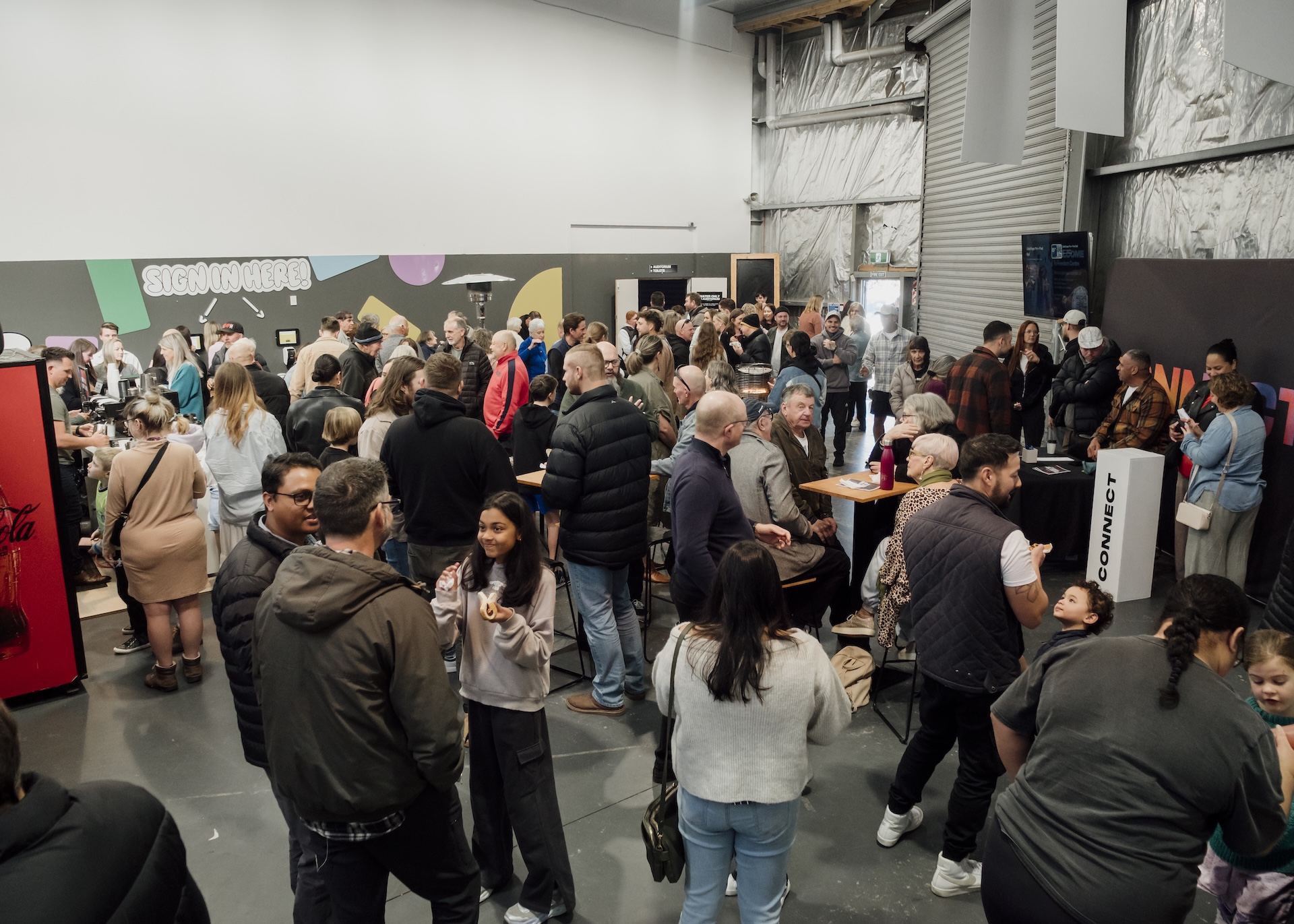 People attending a lively indoor music event with hands raised.