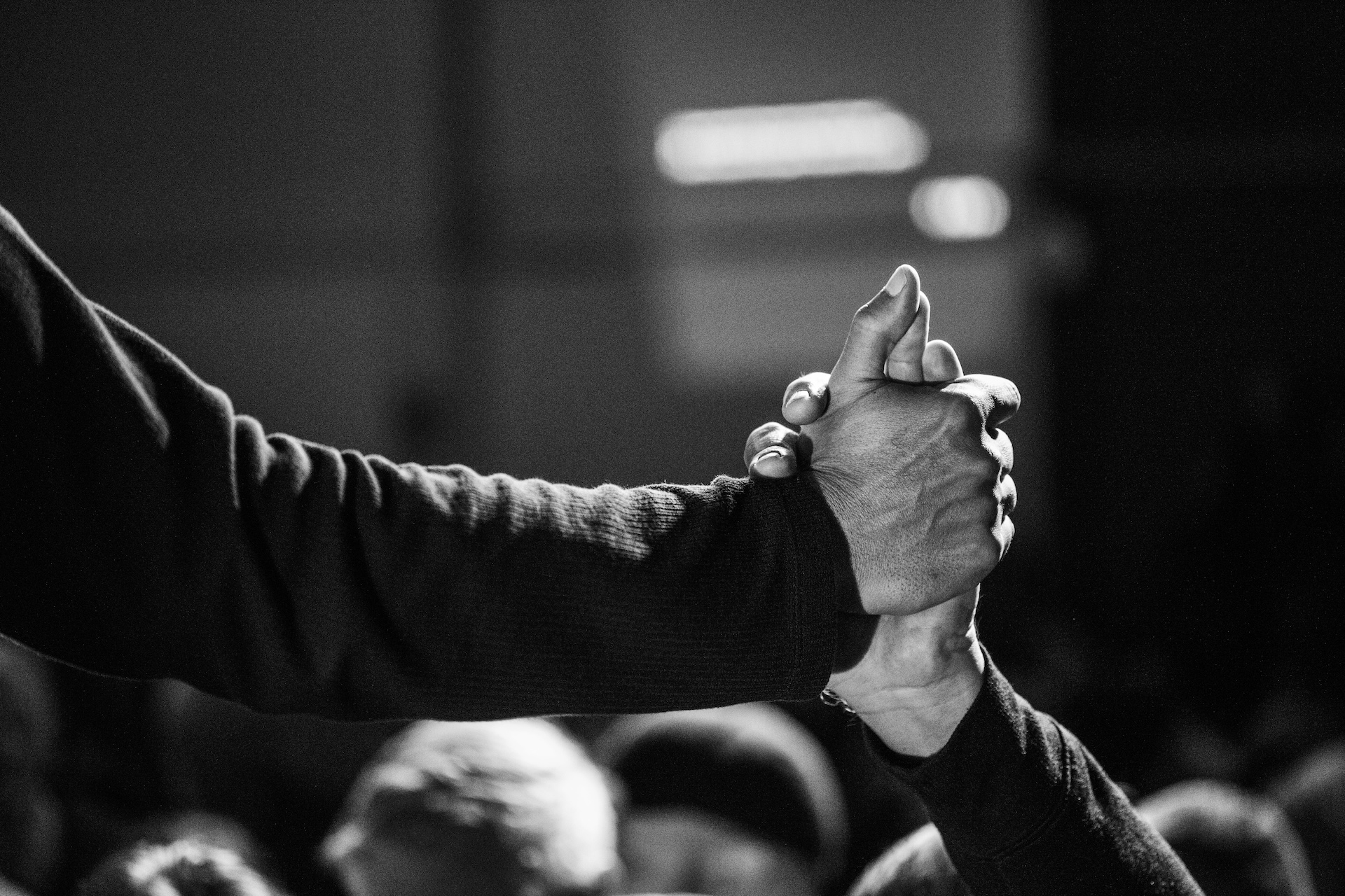 Two women in safety vests smiling outside an industrial building with cars parked nearby.