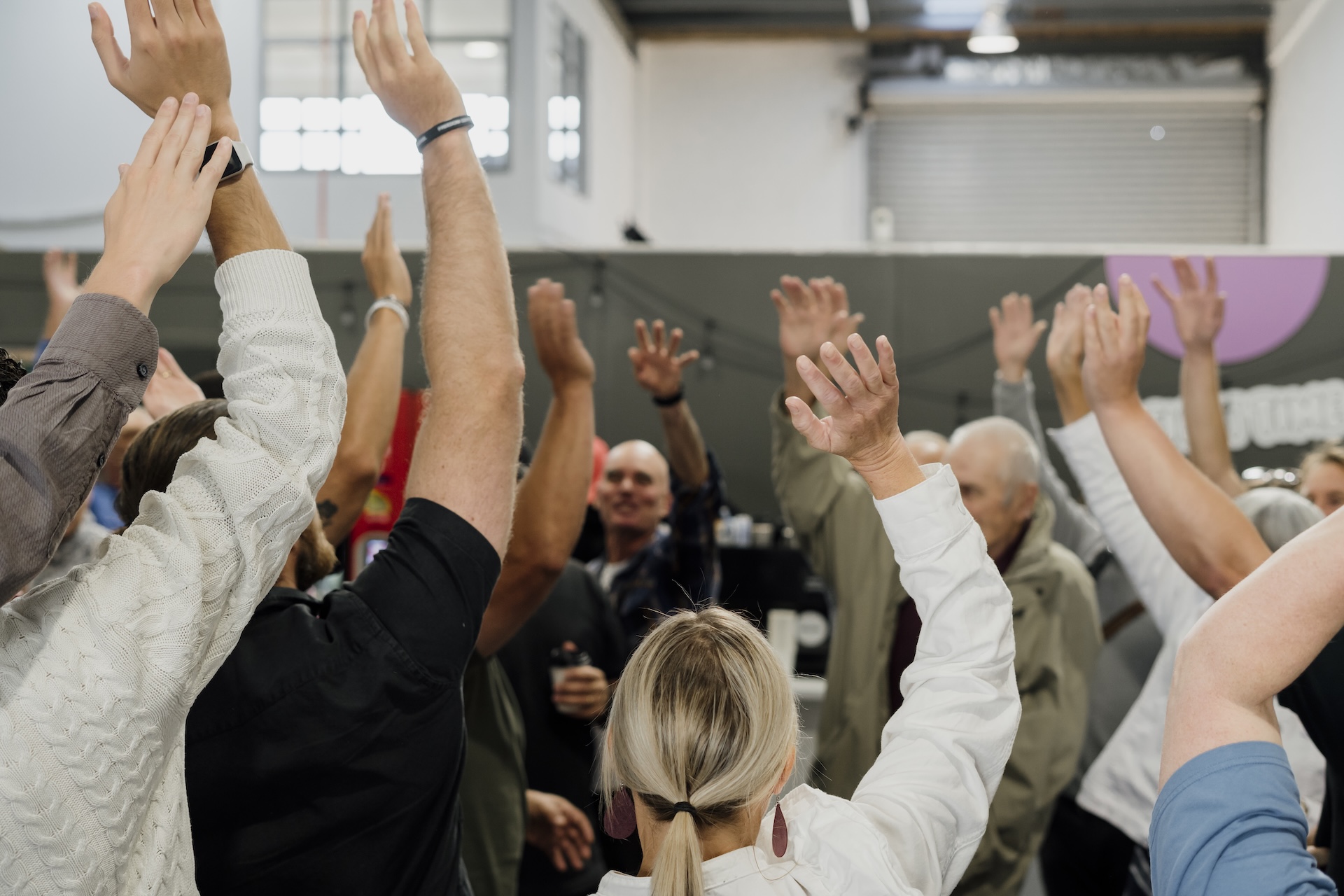Two women in safety vests smiling outside an industrial building with cars parked nearby.