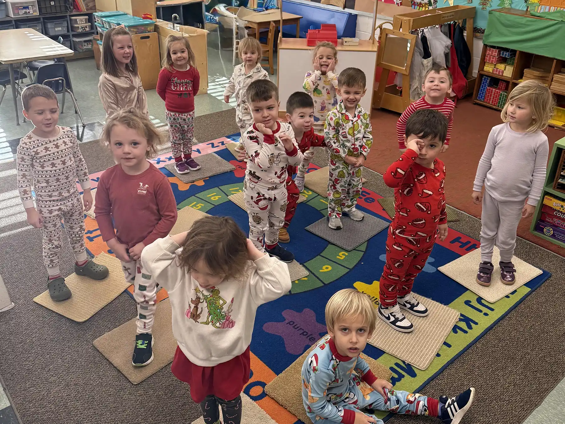 Orange Community Nursery School 3s class students wear festive holiday pajamas in the classroom during their holiday pajama party celebration.