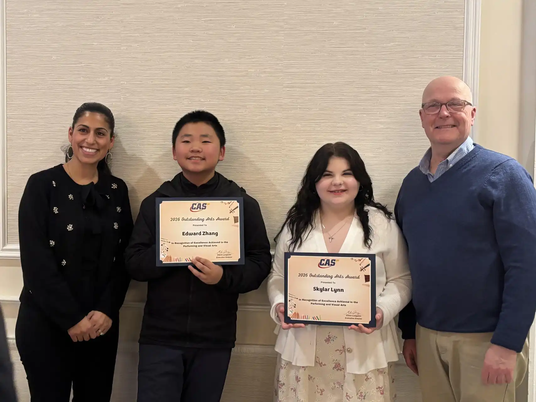 Two students, Edward Zhang and Skylar Lynn, hold their 2026 CAS Outstanding Arts Awards while standing with two adults at a recognition ceremony.