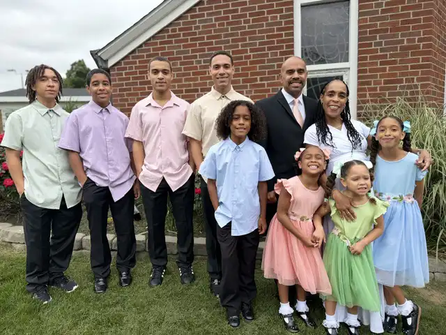 Full family portrait of Drs. Rey and Dennie Ramos and their eight children standing in front of the altar inside Holy Infant Church.