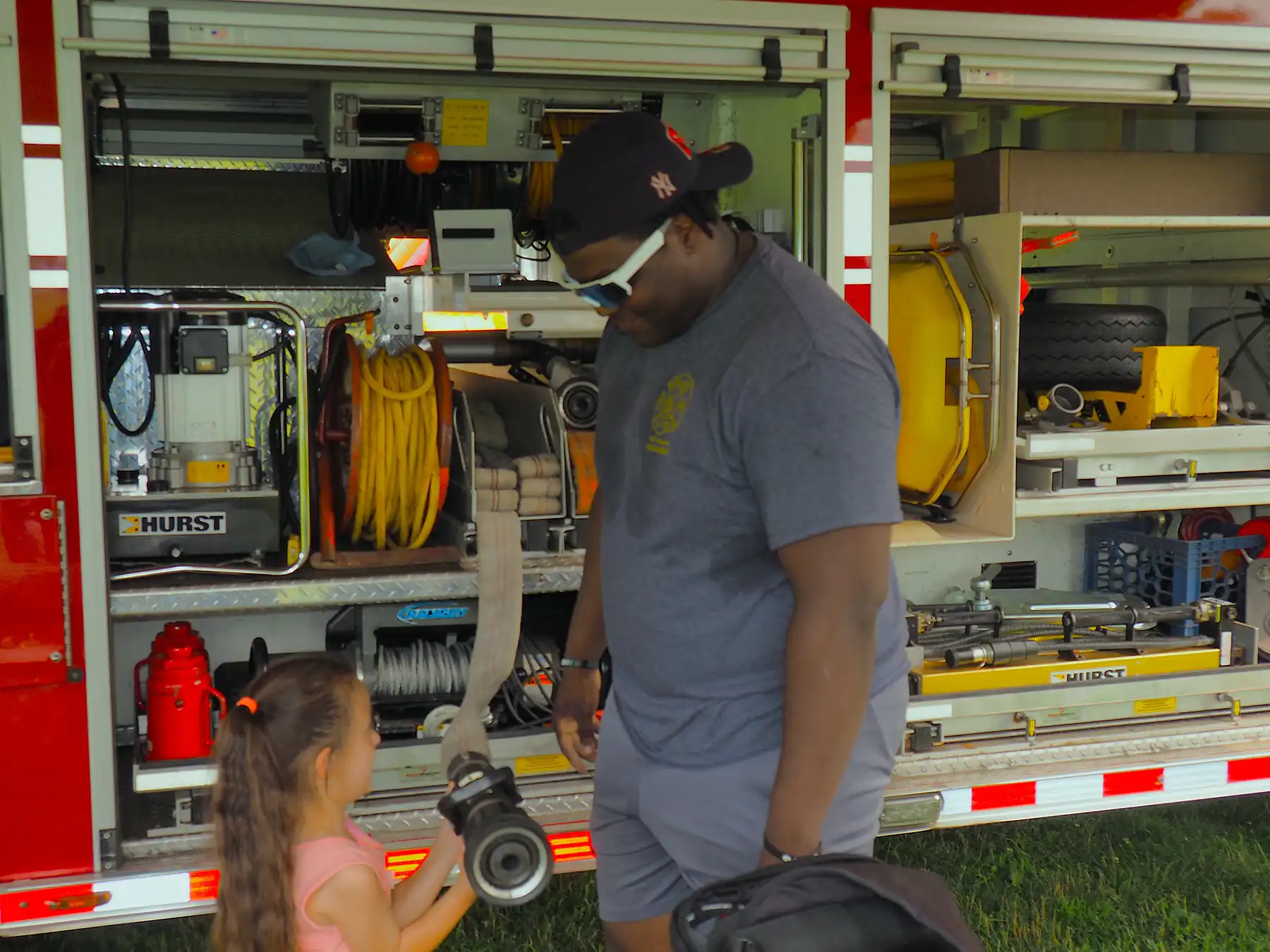Orange firefighter Jasyn Andrews shows a fire truck hose nozzle to a young girl at the Orange Volunteer Fire Department exhibit.
