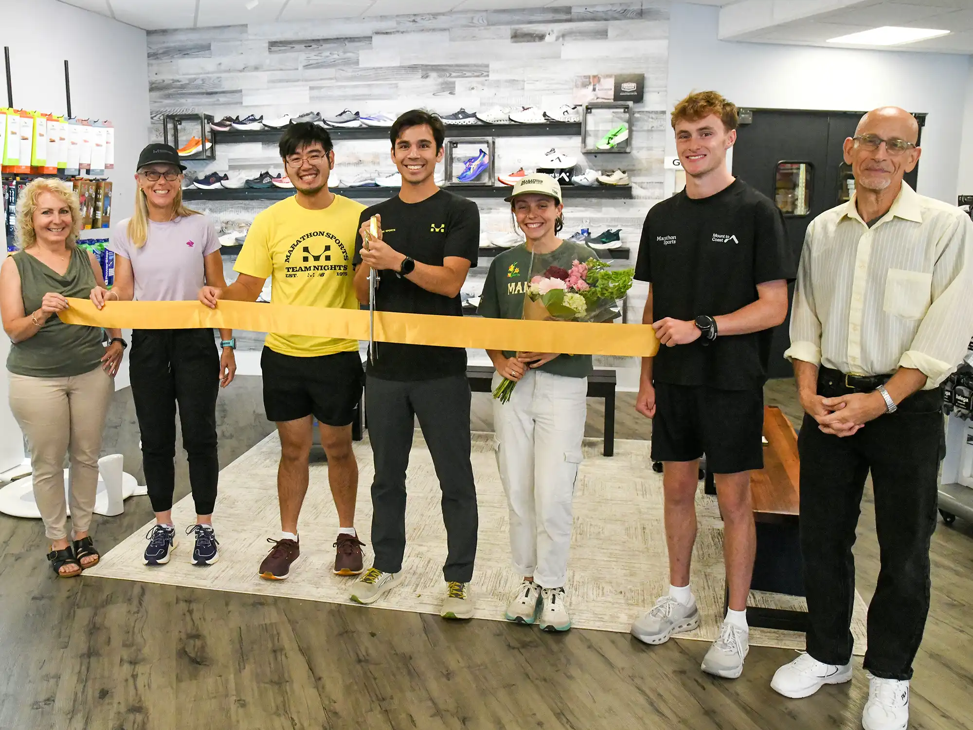 Staff and community leaders cut a yellow ribbon at the Marathon Sports store grand opening ceremony in Orange, Connecticut.