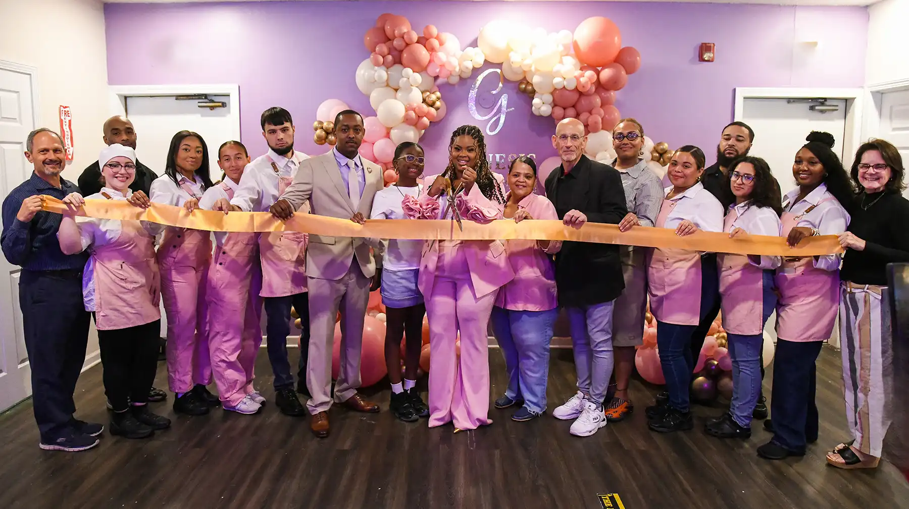 Erica Mcqueen cuts an orange ribbon surrounded by staff and community officials at the Genesis Brunch and Co grand opening celebration in Orange.