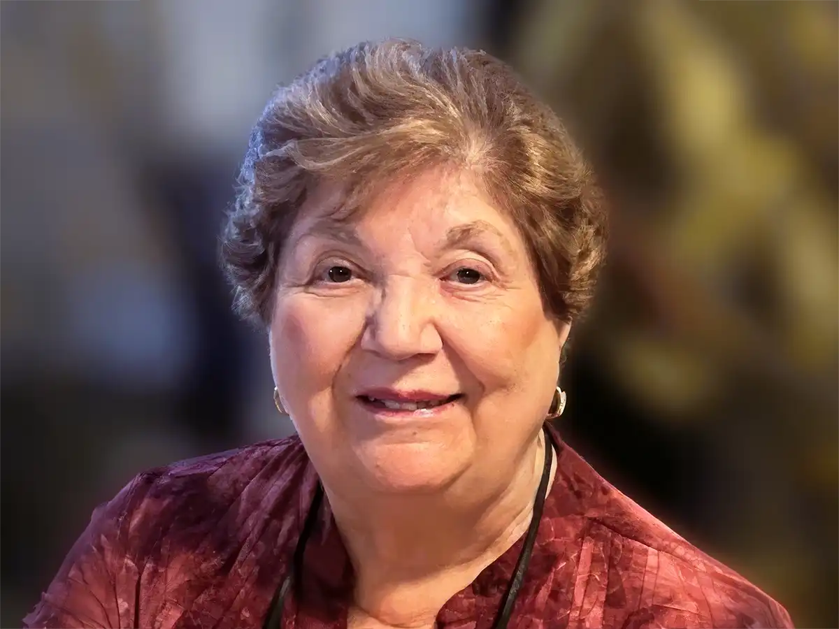Portrait of Marian Drobish smiling warmly in a patterned maroon blouse, longtime Orange educator and founding member of the Orange Players.