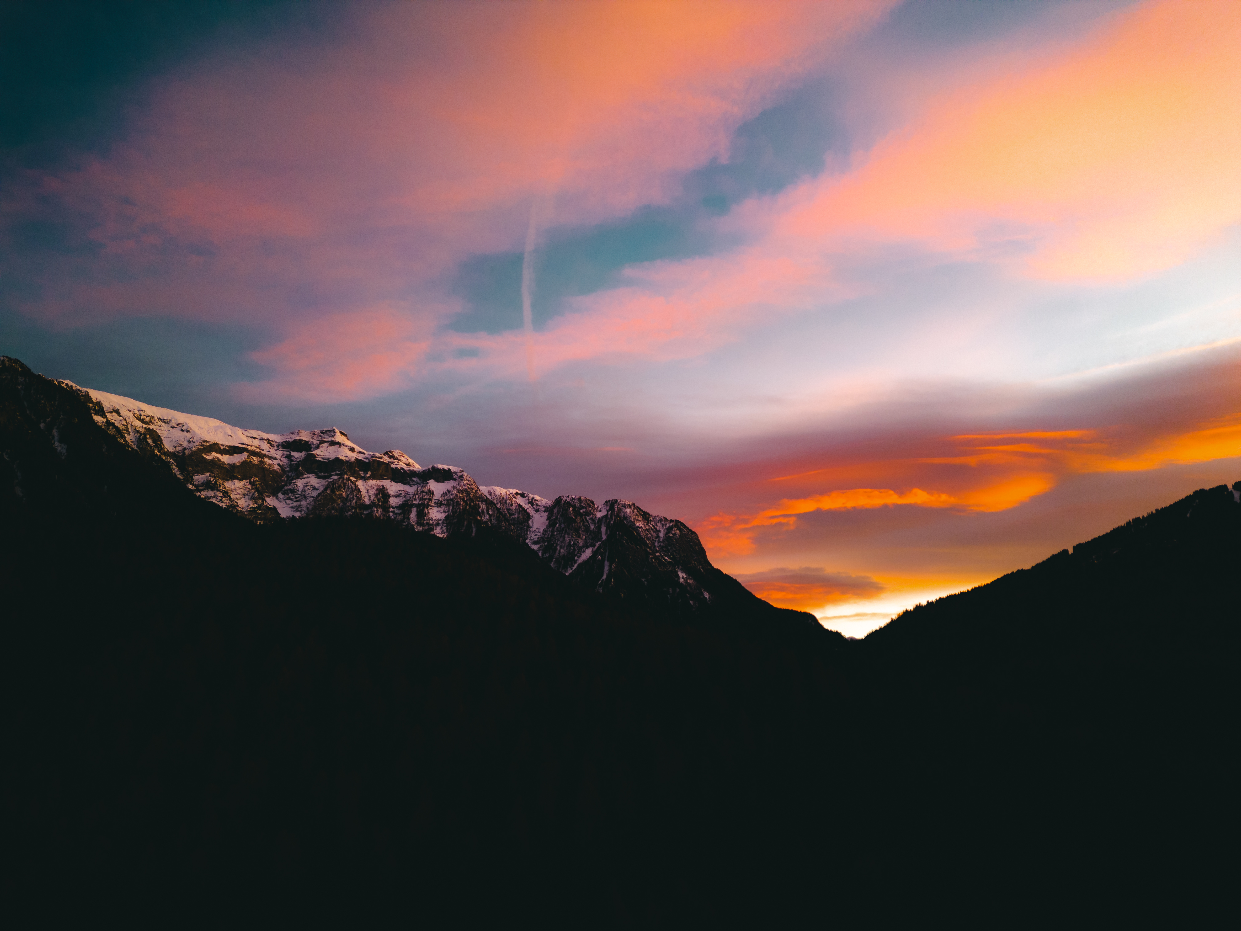 Photo of sunset with bright red and purple colors over mountains, taken from a drone