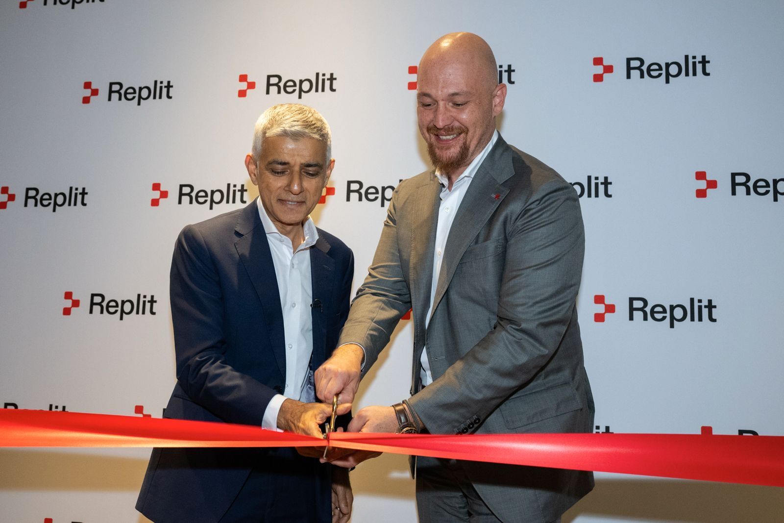 Mayor or London and Replit CEO cutting the ribbon opening the new Replit London location in front of a branded backdrop.