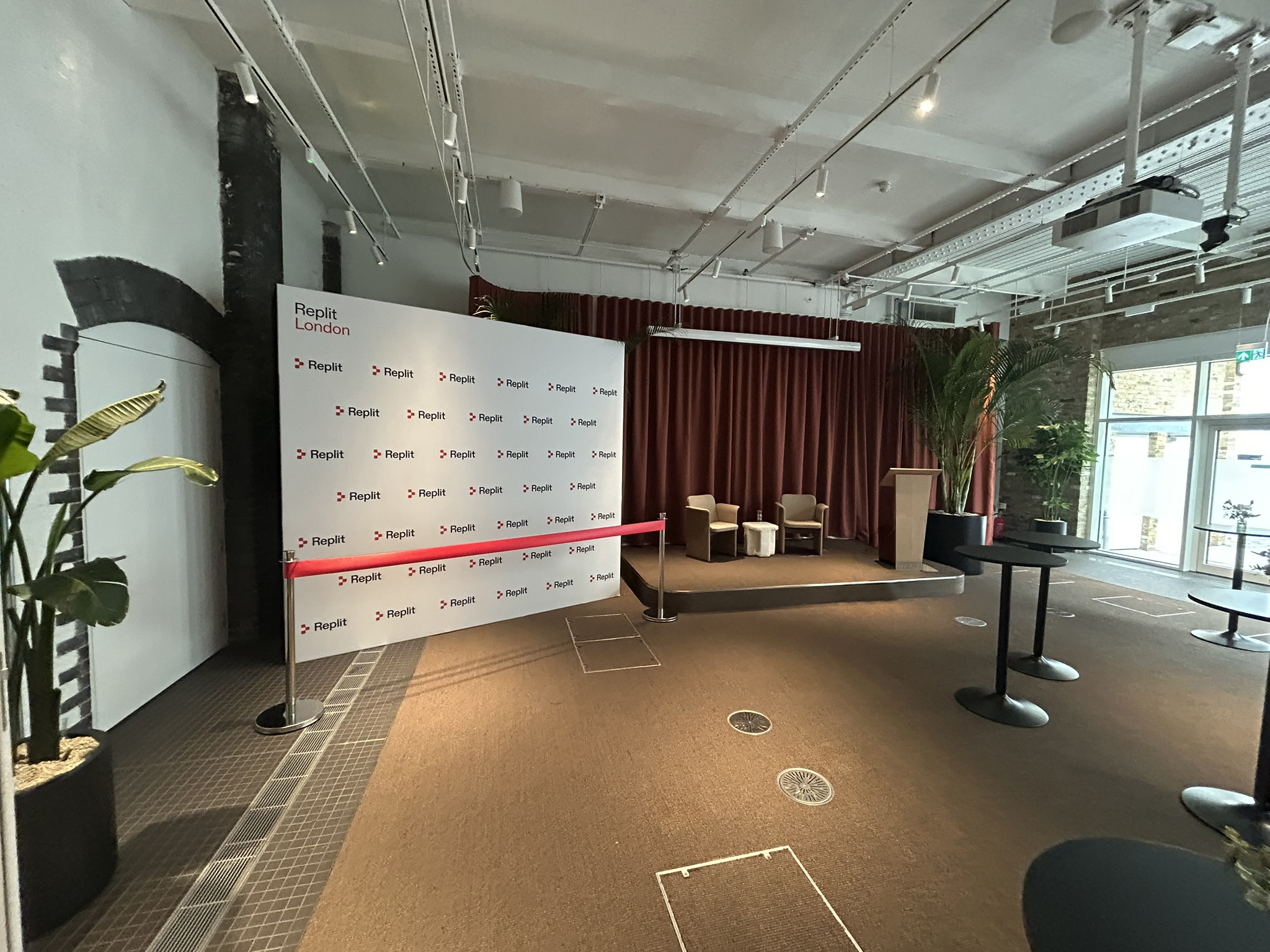 ribbon ready for a opening ceremony next to a stage with a logo wall behind the red ribbon