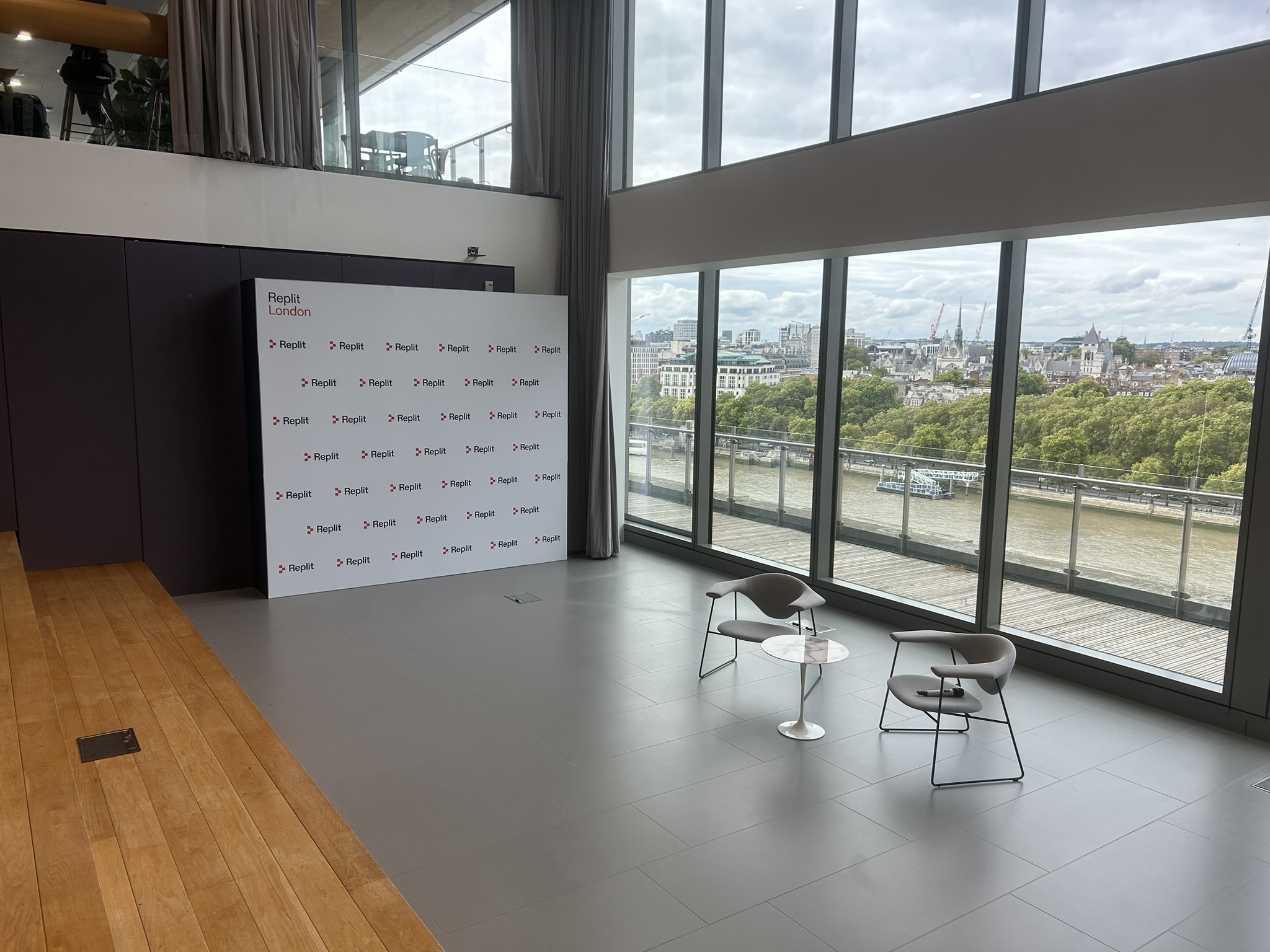 Branded step and repeat wall next to some chair that are infront of a large window for a company keynote at Sea Containers London