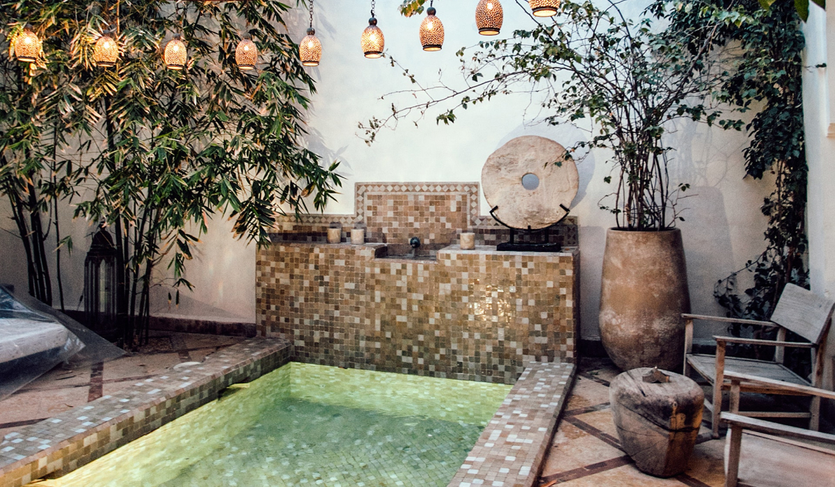 Pool with geometric tile surrounded by lights and plants.