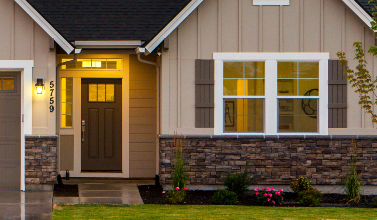 Craftsman home with beige siding and stone veneer skirting at dusk