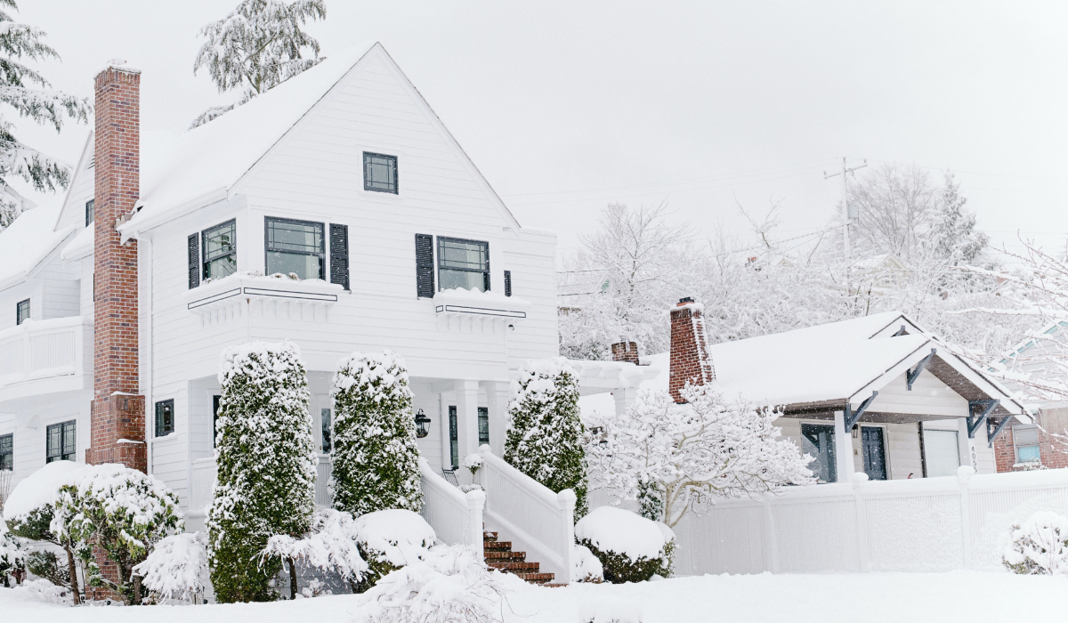 White lap siding home with brick chimney in a snowy setting