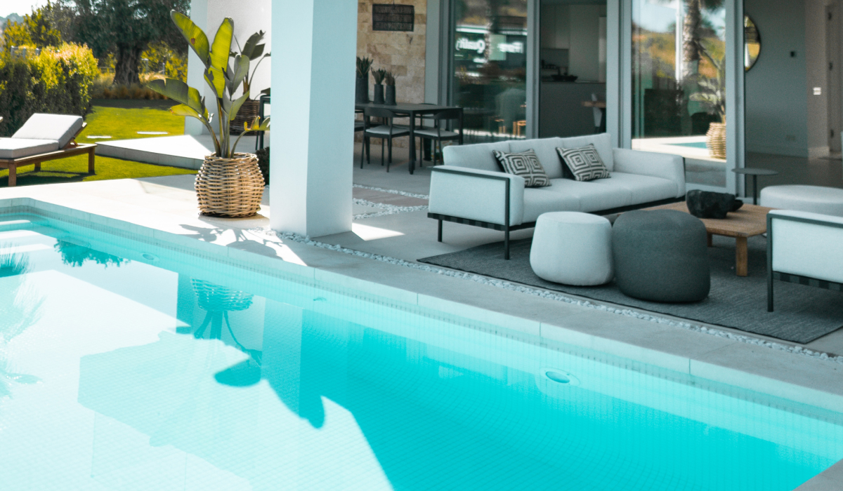 Poolside patio with modern outdoor furniture and sliding glass doors to the home