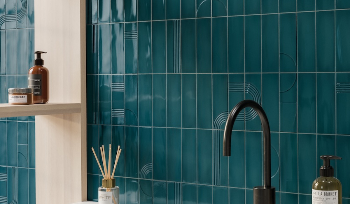 Close-up of a glossy teal subway tile backsplash with an arched geometric pattern, paired with a matte black gooseneck faucet.