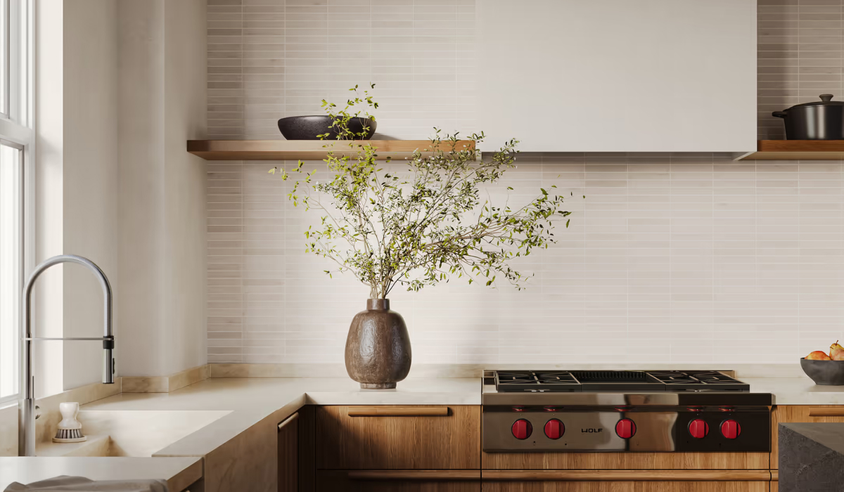 Modern kitchen with a linear tile backsplash, wood open shelving, a white waterfall countertop, and a stainless steel Wolf range with red knobs.