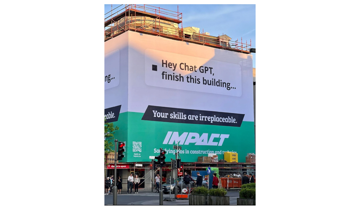 Large building-wrap billboard for Impact reading "Hey ChatGPT, finish this building... Your skills are irreplaceable," advertising construction and technical jobs, on a scaffolded street-corner building.