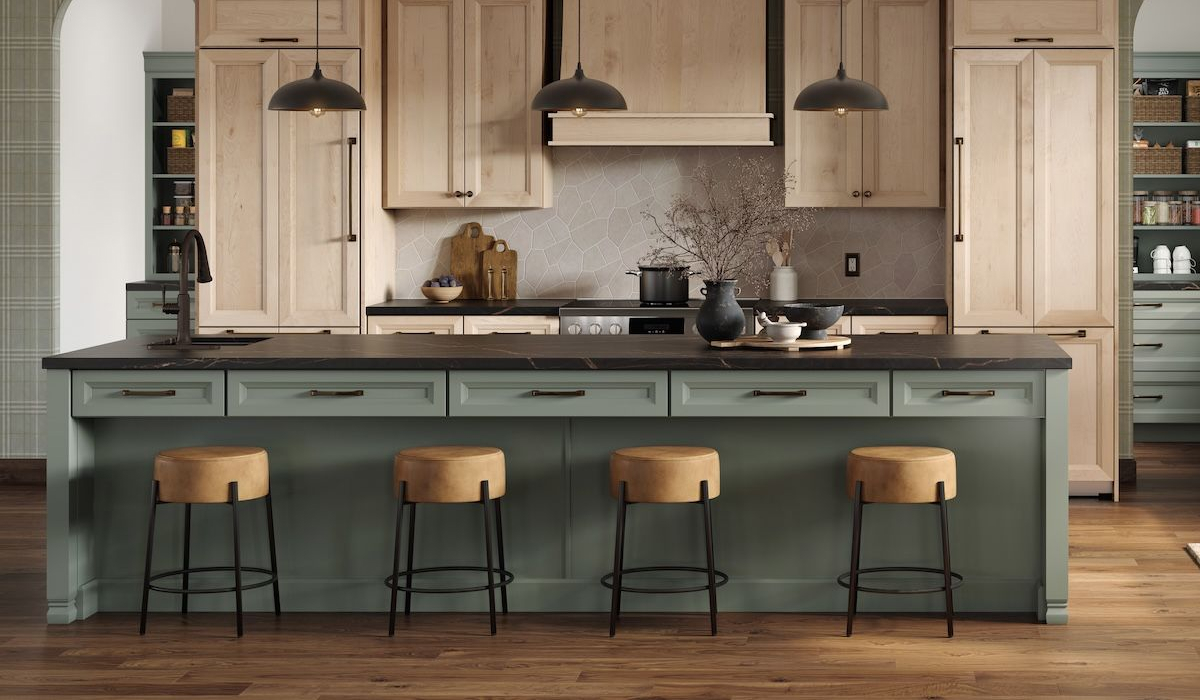 Sage green kitchen island with black soapstone countertop, natural wood cabinetry, and leather counter stools