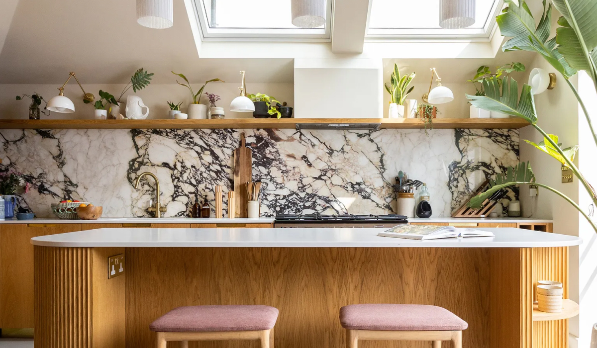 Sunlit kitchen with dramatic purple-and-white marble backsplash, wood island, and skylights filled with plants