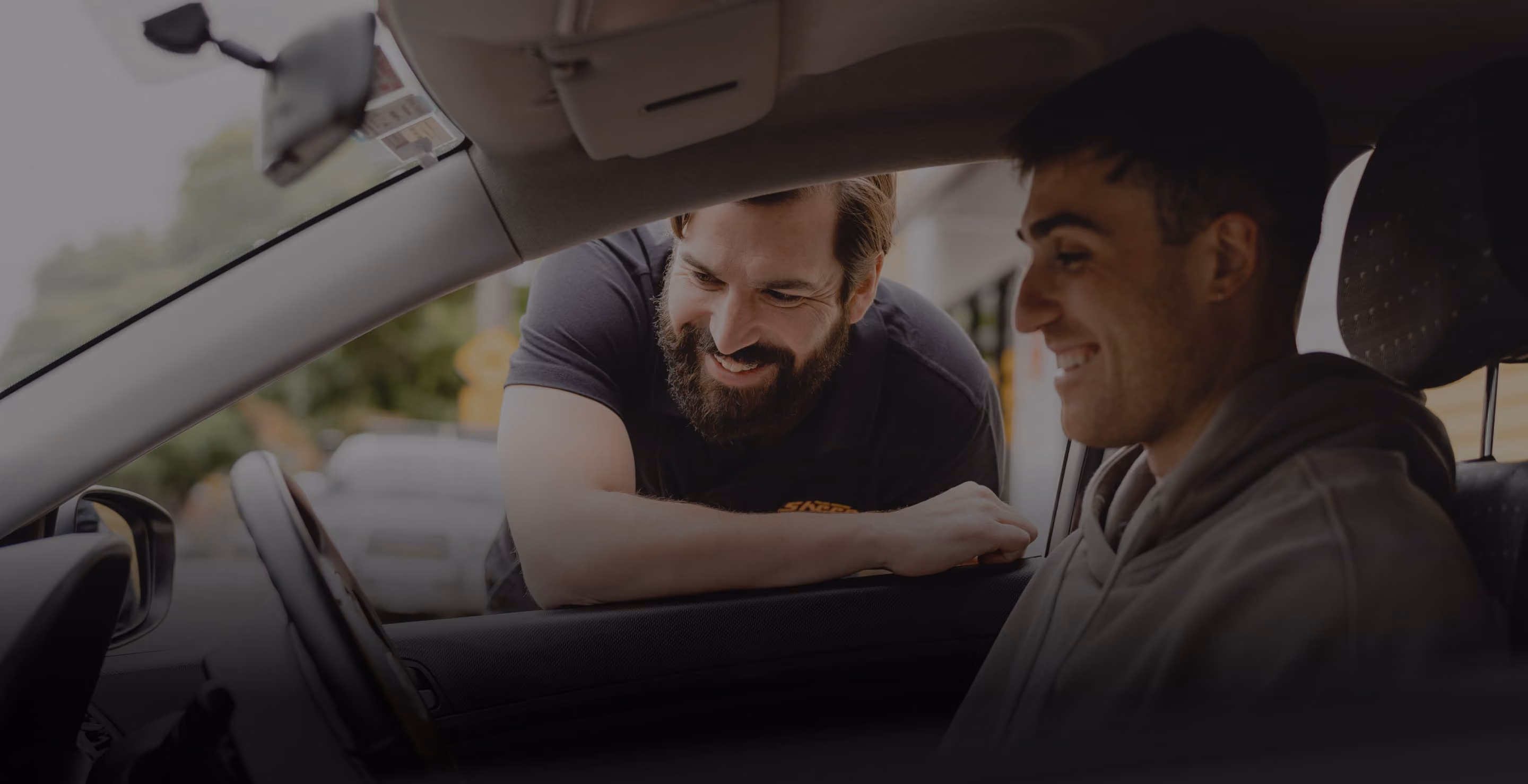 Wide banner image featuring a car repair workshop scene with multiple vehicles and technicians in action.