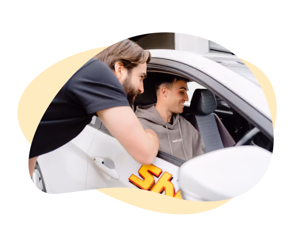 Image of a man inside a Sheen vehicle and a Sheen member talking to him through the window. 