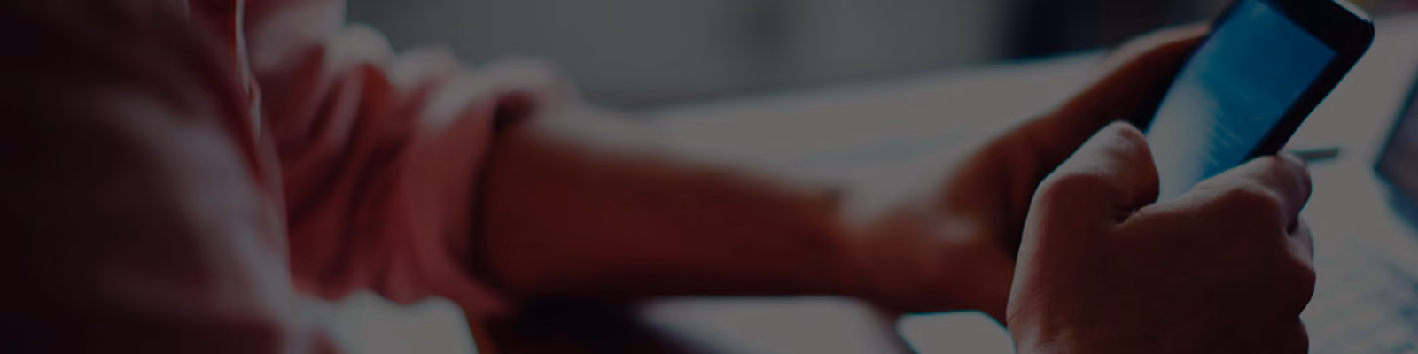 Banner image of a man intently using his mobile phone in a modern office setting.