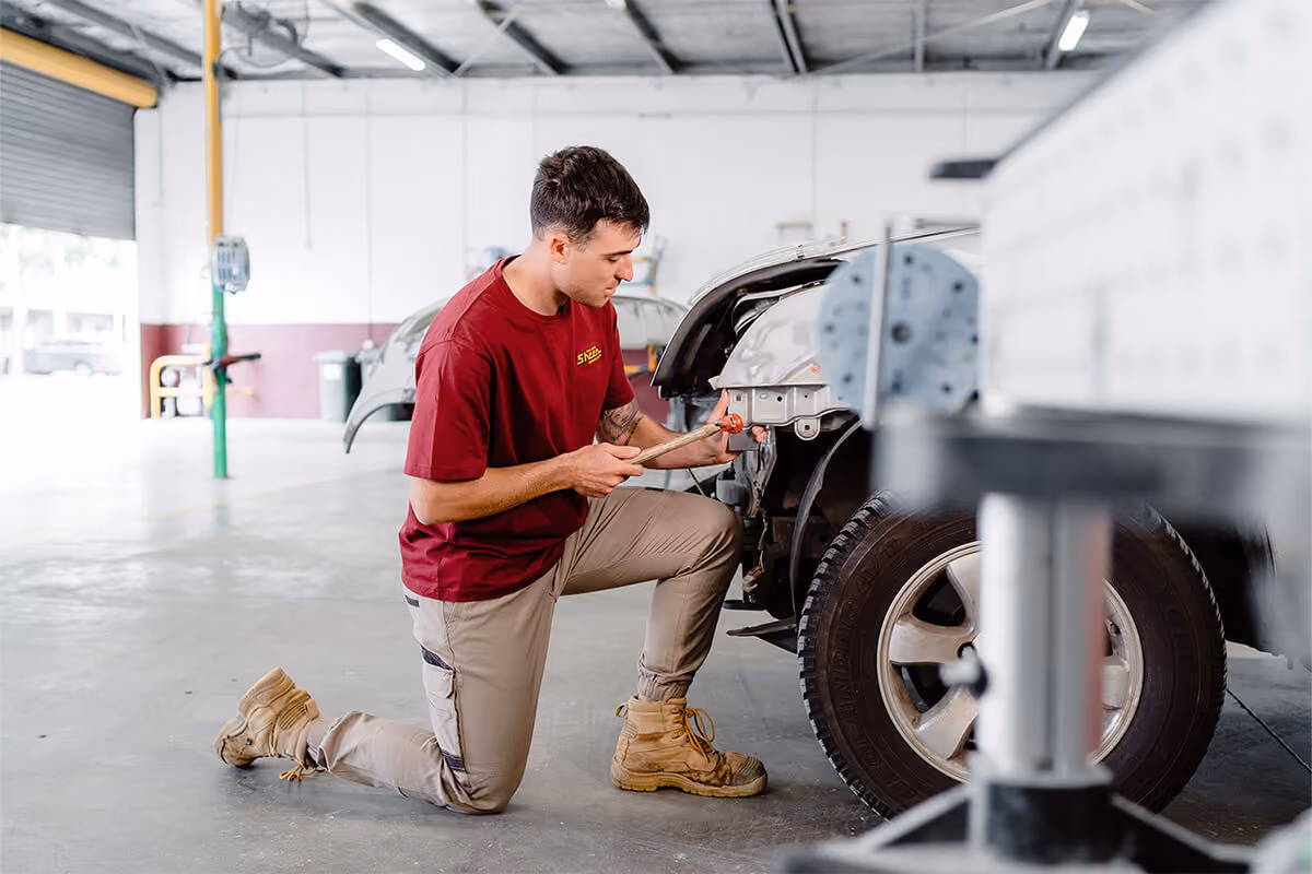 Sheen worker using equipment to fix the front of a car.