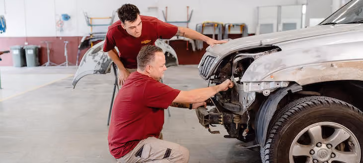 Photo inside Sheen's workshop showing technicians and cars in repair.