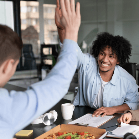 People at a restaurant high-fiving as an example of sales incentives for customers that work.