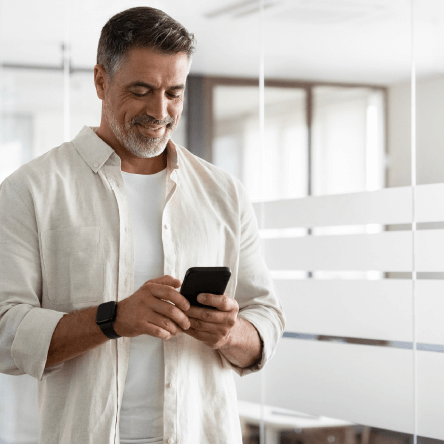 A man smiling at his phone, meant to represent a happy person receiving an eco-friendly corporate gift.