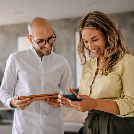 Employees looking happily at a phone, meant to represent the positive influence of employee incentive programs. 