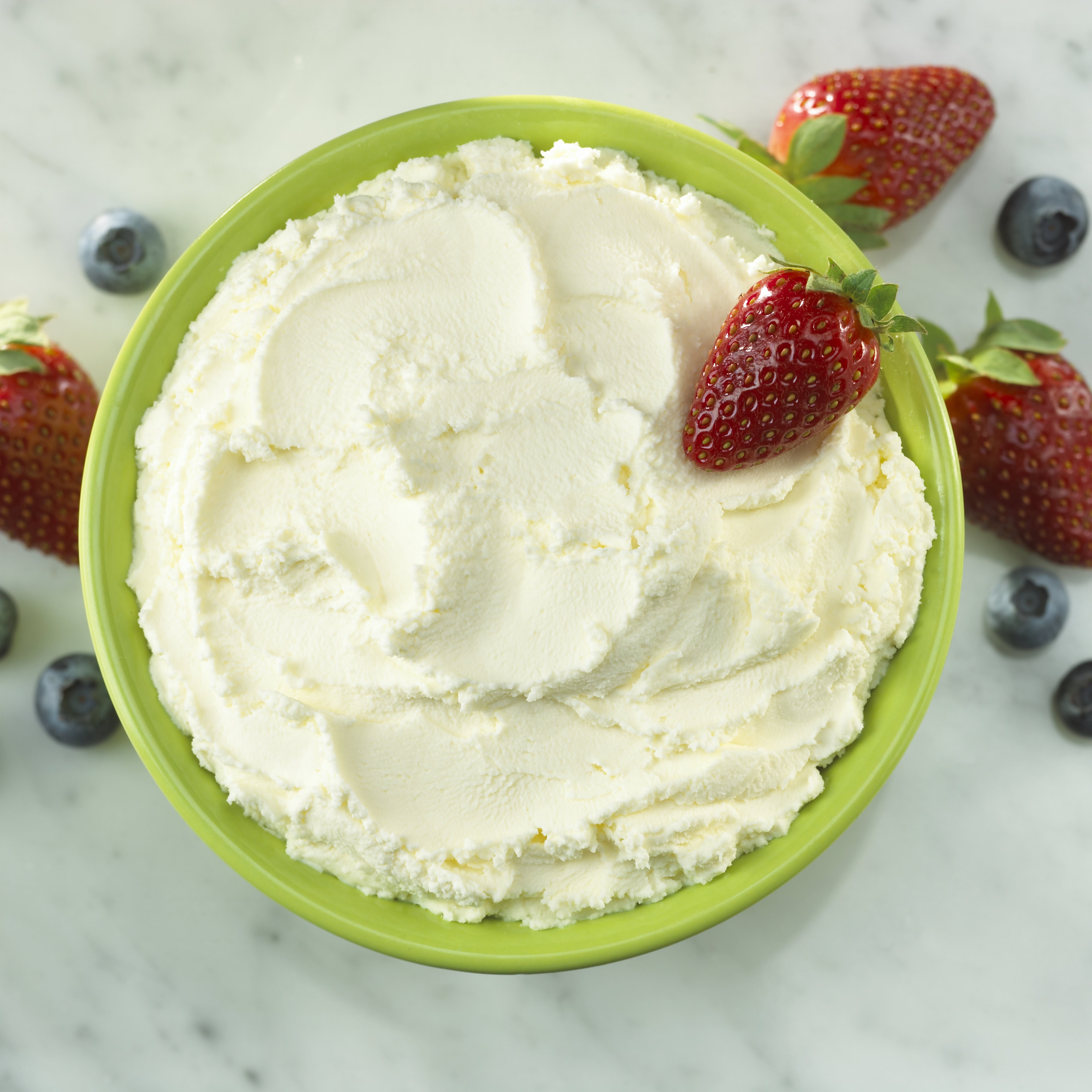 A green bowl of Miceli's mascarpone cheese garnished with fresh berries