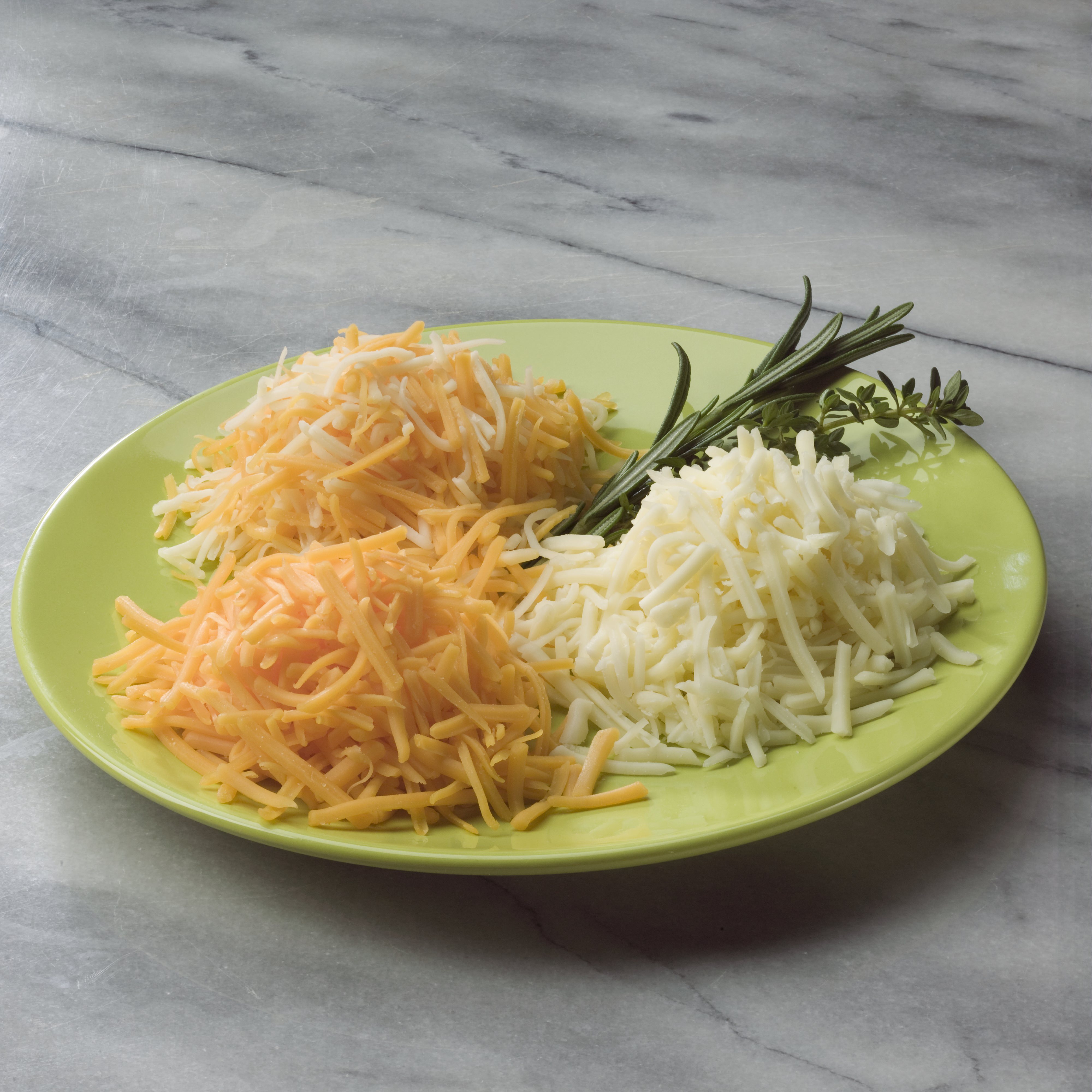 A green plate of Miceli's Shredded Cheese garnished with fresh herbs