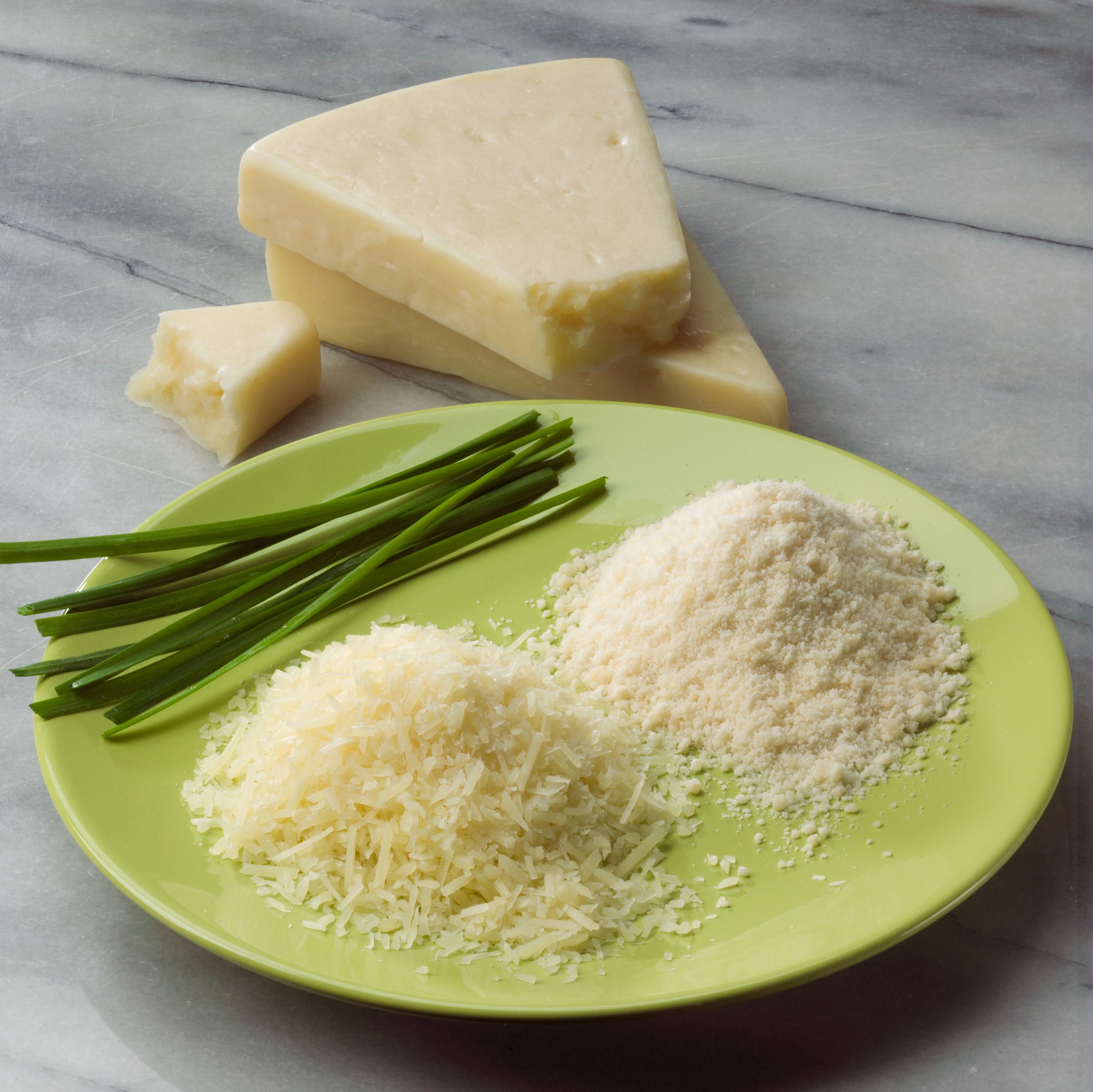 A green plate of Miceli's Parmesan Cheese garnished with fresh herbs