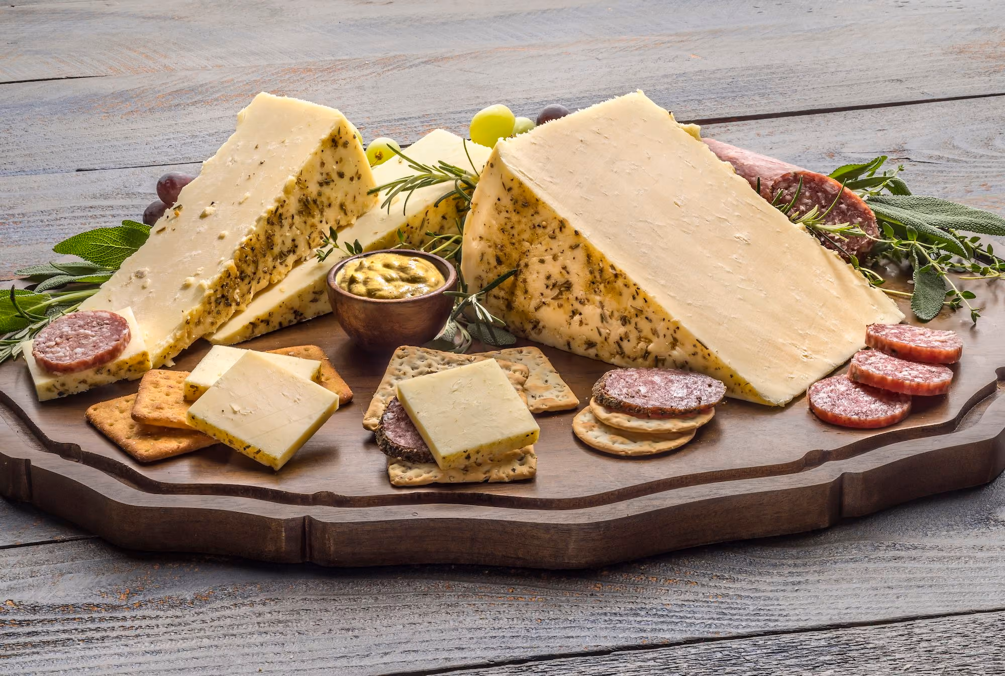 Mustard and herb rubbed cheddar displayed on a charcuterie board. 