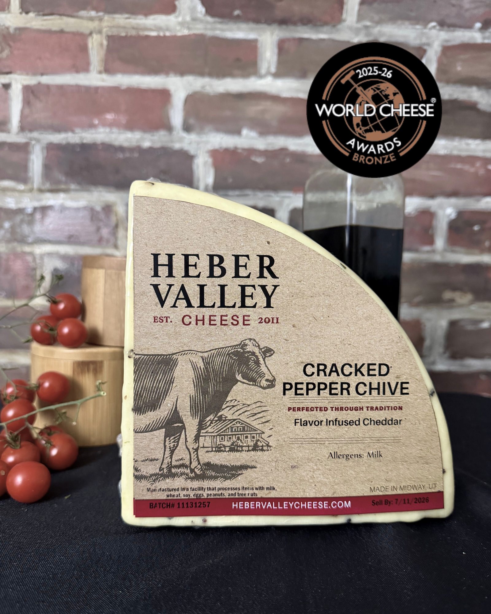 A quarter wedge of Heber Valley Cheese with tomatoes and balsamic vinegar in the background. 