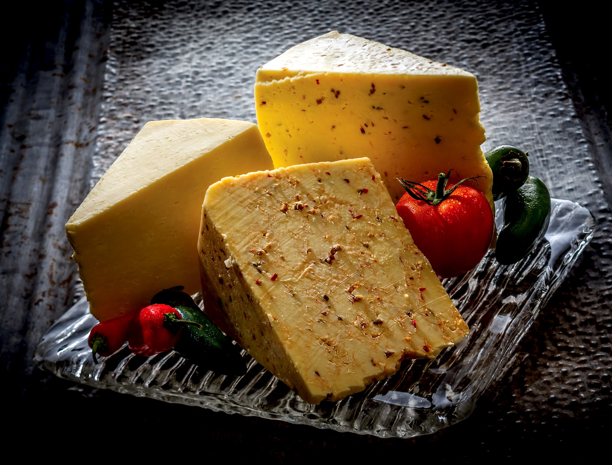 Three wedges of cheese displayed with fresh salsa ingredients 
