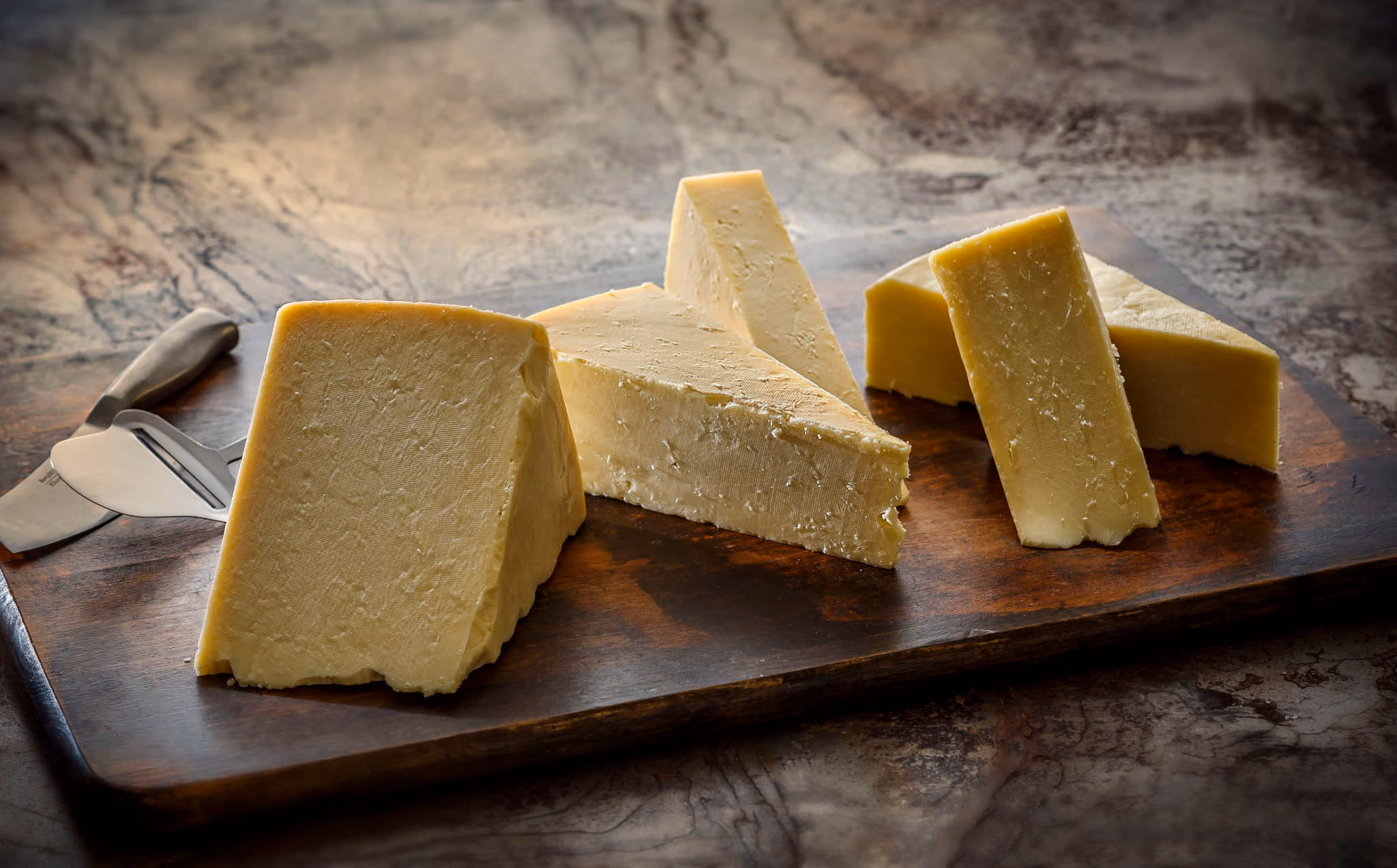 Fresh wedges of white Holstein cheddar on a cutting board.